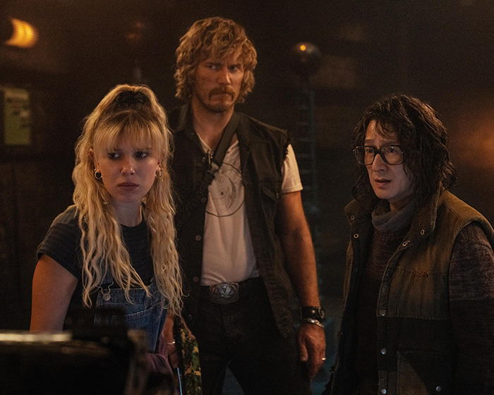 Three people in a dimly lit room with intense expressions. Three people in a dimly lit room with intense expressions.