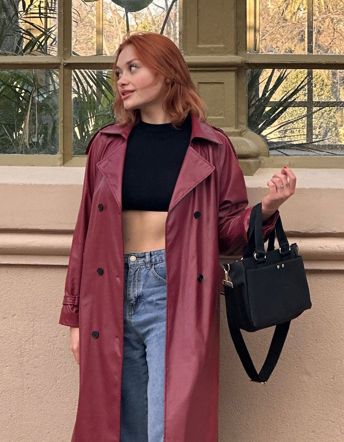 Red-haired woman in a maroon trench coat holding a handbag, related to model’s assault case and possible trafficking. Red-haired woman in a maroon trench coat holding a handbag, related to model’s assault case and possible trafficking.