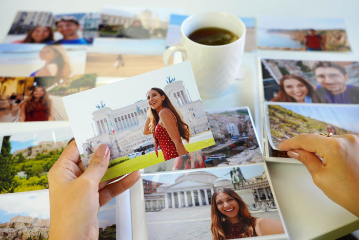 Person holding photos with a cup of tea in the background, depicting memories related to husband's late wife. Person holding photos with a cup of tea in the background, depicting memories related to husband's late wife.