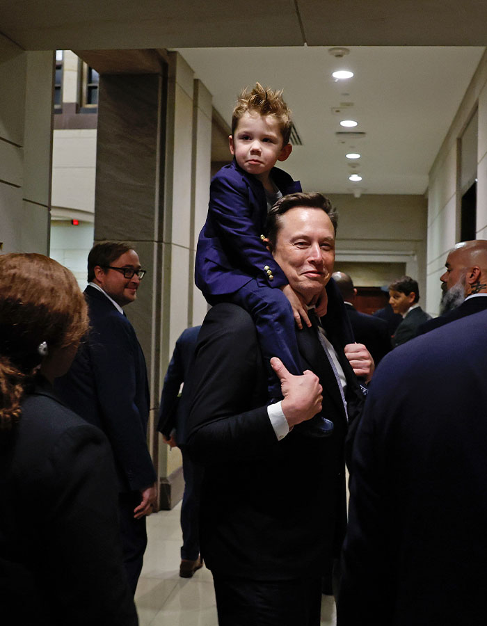 Man carrying a child on his shoulders in a formal setting, surrounded by people. Man carrying a child on his shoulders in a formal setting, surrounded by people.