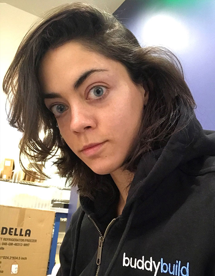 Person wearing a black buddybuild hoodie, sitting in a room with boxes, partially visible; related to Elon Musk news. Person wearing a black buddybuild hoodie, sitting in a room with boxes, partially visible; related to Elon Musk news.