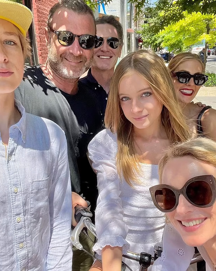 Group selfie outdoors, including Naomi Watts and others, with her teen daughter in the center wearing a white blouse. Group selfie outdoors, including Naomi Watts and others, with her teen daughter in the center wearing a white blouse.