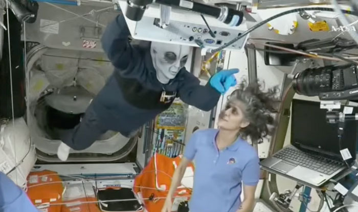 SpaceX crew member in costume on ISS interacting with NASA astronaut amidst Halloween-themed fun. SpaceX crew member in costume on ISS interacting with NASA astronaut amidst Halloween-themed fun.