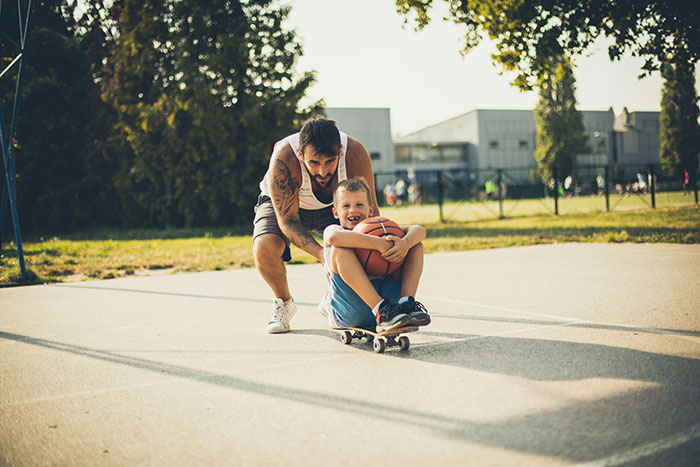 Adult guiding a child on a skateboard, demonstrating negative reinforcement to help kids overcome fears in a park setting. Adult guiding a child on a skateboard, demonstrating negative reinforcement to help kids overcome fears in a park setting.