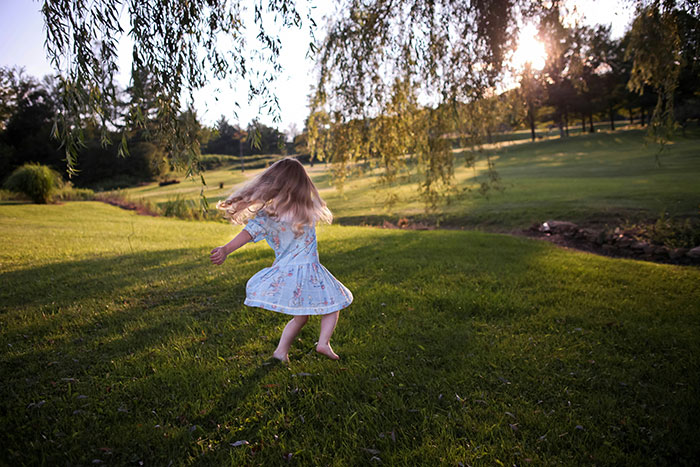 Child playing outdoors, spinning happily on grass. Parenting expert discusses using negative reinforcement to help overcome fear. Child playing outdoors, spinning happily on grass. Parenting expert discusses using negative reinforcement to help overcome fear.