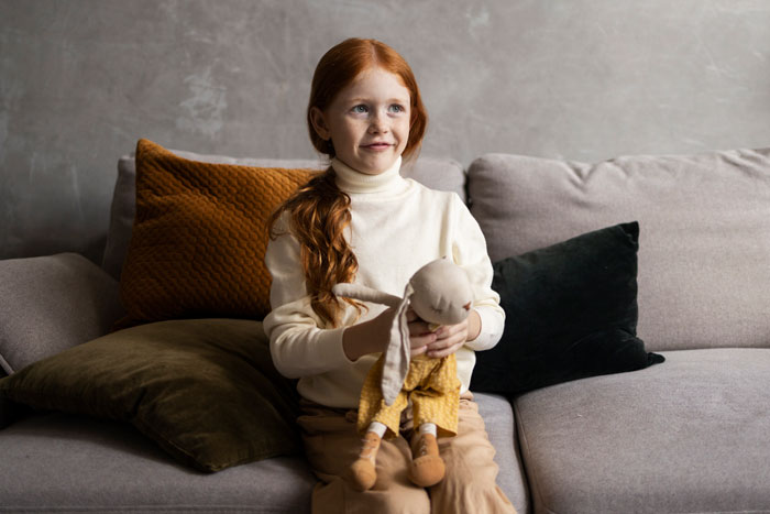 Child holding a doll on a sofa, related to a customized toy for a "Golden Child. Child holding a doll on a sofa, related to a customized toy for a "Golden Child.