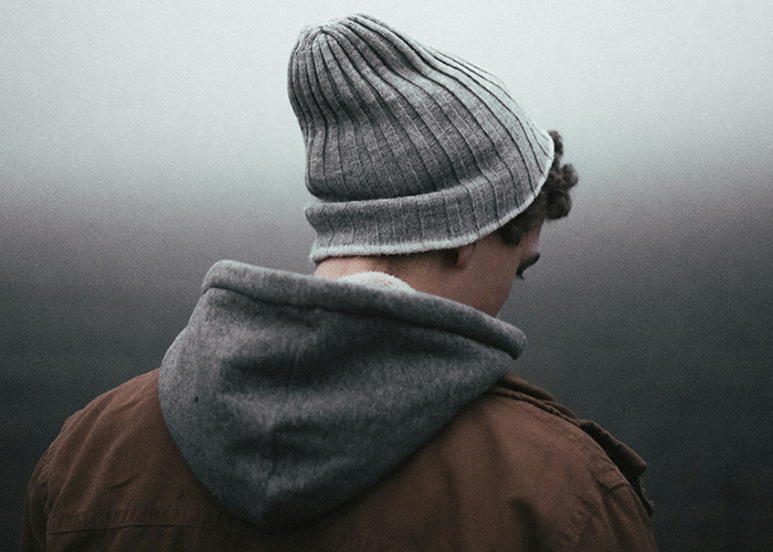 Person in winter clothes with head down, evoking childhood trauma reflection.