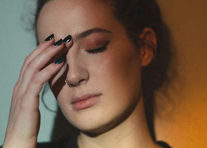 Person with a pensive expression, hand on forehead, symbolizing childhood trauma.