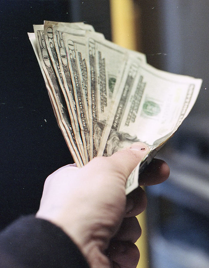 Hand holding a fan of US dollar bills, symbolizing financial transaction or reward. Hand holding a fan of US dollar bills, symbolizing financial transaction or reward.