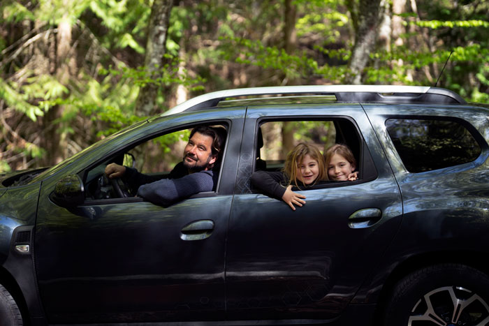 Man and two step-siblings smiling in a car, enjoying a family drive through the forest. Man and two step-siblings smiling in a car, enjoying a family drive through the forest.