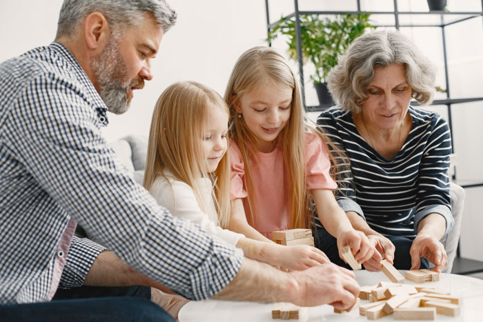 Family playing with wooden blocks at home, including stepsiblings, enjoying a fun and engaging activity together. Family playing with wooden blocks at home, including stepsiblings, enjoying a fun and engaging activity together.