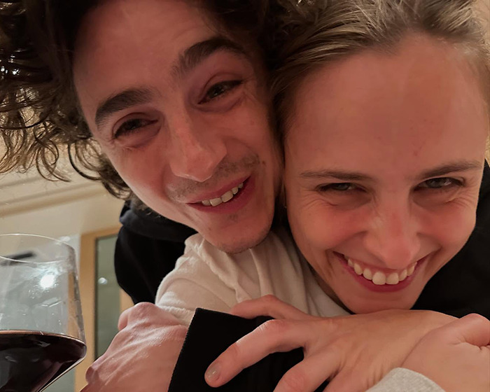 Two people smiling together closely, holding a glass of red wine. Two people smiling together closely, holding a glass of red wine.