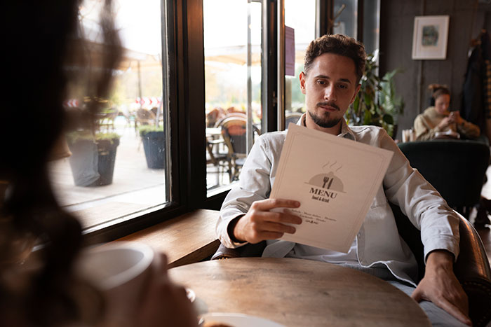Man in a cafe reading a menu, relaxed atmosphere, natural light reflecting generational preferences in dining.