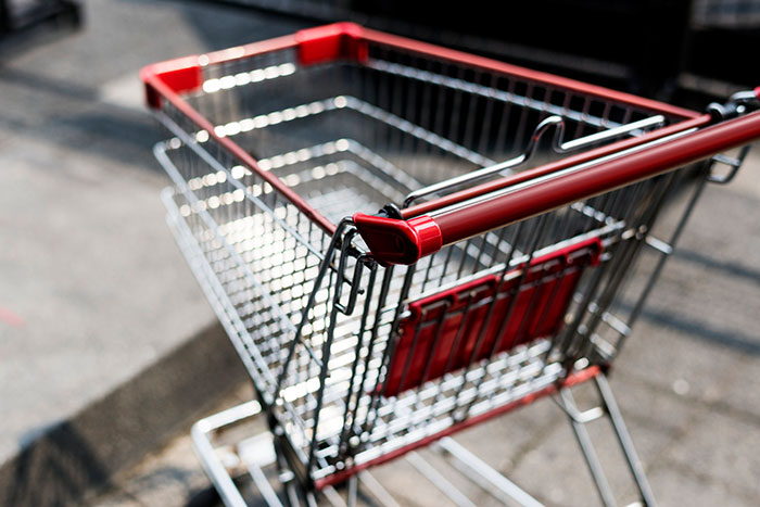 Shopping cart in a parking lot with red handles, showcasing a design boomers might appreciate.