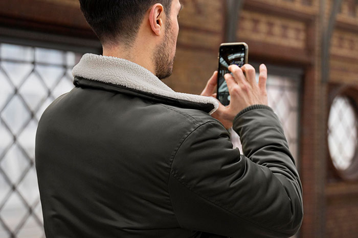 Person in a green jacket using a smartphone, highlighting connection with older generations.