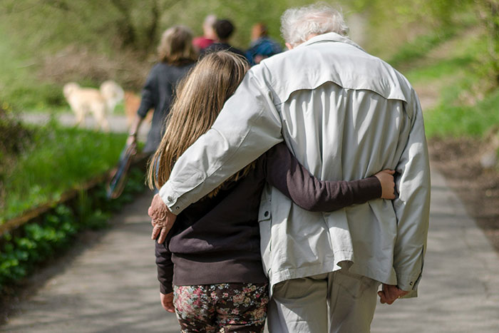 Grandparent and child walking closely on a path, highlighting the wisdom of older generations.