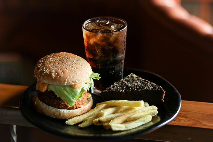 Platter of classic burger, fries, pie, and cola reflecting boomer-era meal preferences on a wooden table.