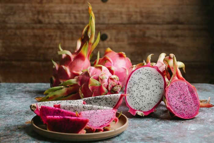 Unusual foods: sliced and whole dragon fruit on a rustic table. Unusual foods: sliced and whole dragon fruit on a rustic table.