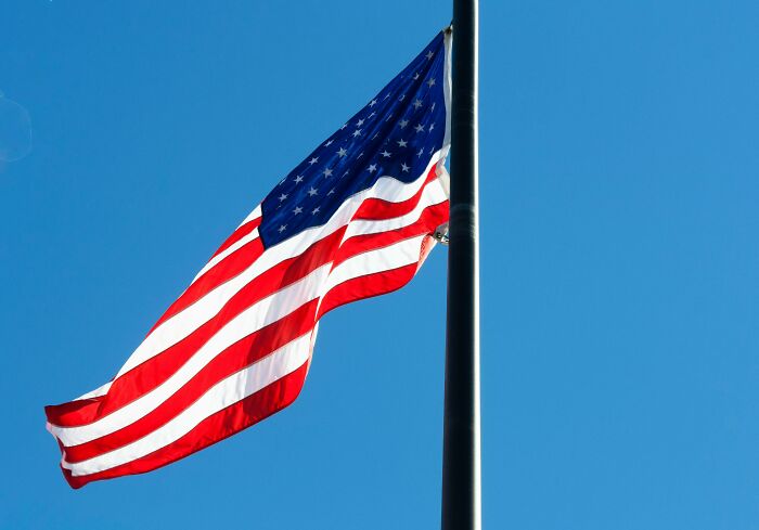 U.S. flag waving against a clear blue sky during citizenship test preparation. U.S. flag waving against a clear blue sky during citizenship test preparation.