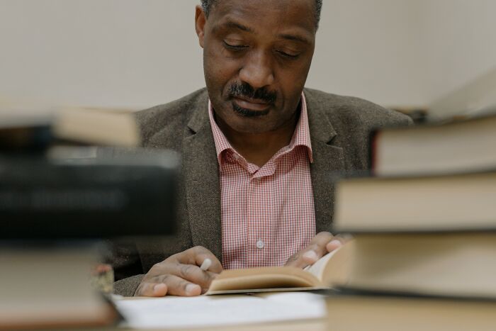 Man reading at a desk surrounded by books, challenging common stereotypes through knowledge.