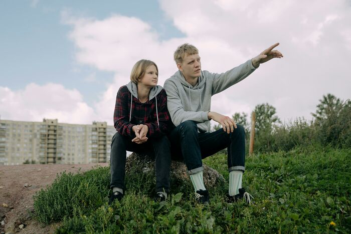 Two people sitting outdoors, with one pointing at the sky, illustrating an insignificant thing stuck in time.