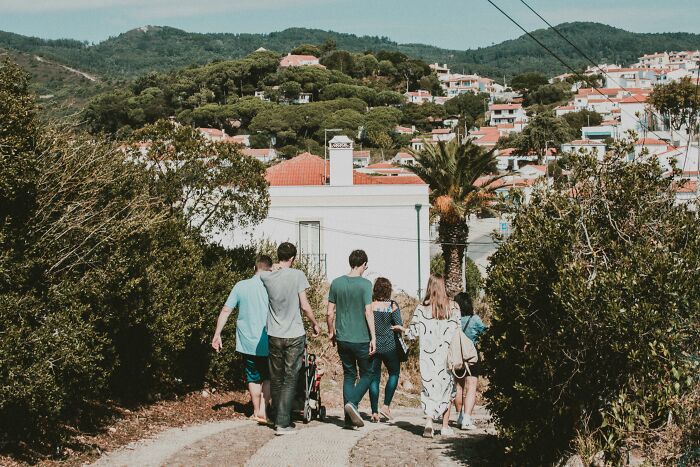 Group walking along a path in a small town surrounded by greenery, evoking feelings of being picked last in gym class.