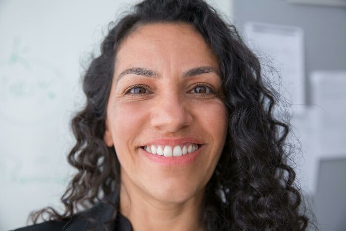 Smiling woman standing against a whiteboard, challenging common stereotypes online.