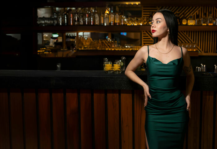 "Woman in a green dress at a bar, exemplifying unprofessional work attire amid a stylish backdrop."