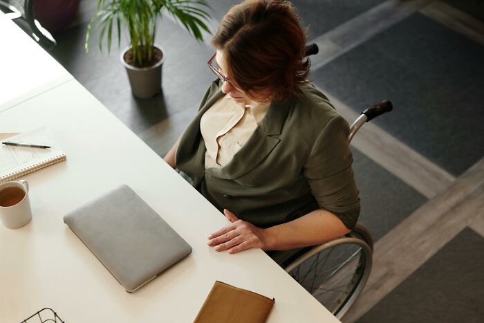 Person in wheelchair working at desk with laptop, challenging common stereotypes about disabilities.