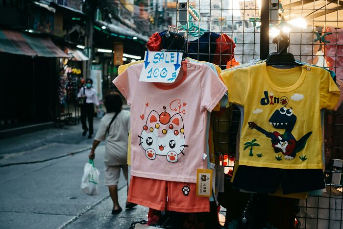 Children's clothing on sale in a street market, featuring cute cartoon designs, showcasing gradually disappeared trends.