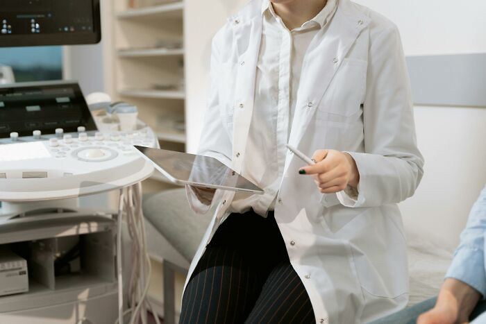 Doctor in a white coat holding a tablet in a medical office setting, embodying heartfelt compliments and care.