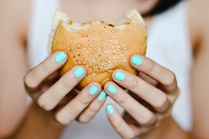 Person holding a burger with sesame seed bun, showcasing the concept of misconceptions.