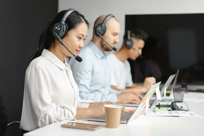 Three people in a call center setting wearing headsets, illustrating careers post-"useless" degrees.