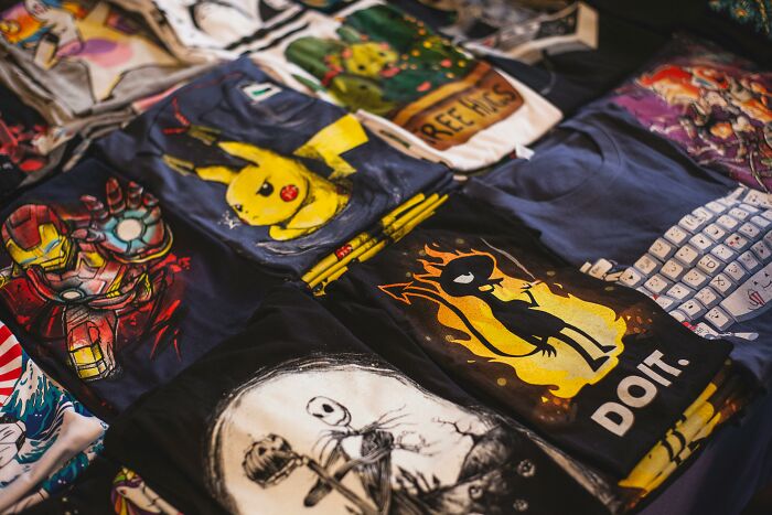 Unprofessional work attire featuring graphic tees with pop culture designs laid out on a table.