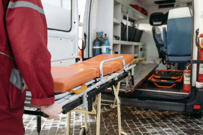 Paramedic pushing a stretcher into an ambulance, representing common misconceptions about emergency medical services.