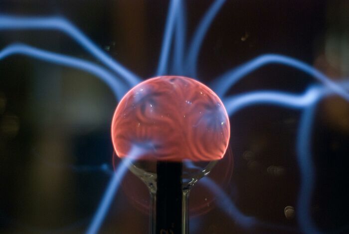 Plasma globe emitting blue and pink lightning, showcasing science general knowledge. Plasma globe emitting blue and pink lightning, showcasing science general knowledge.