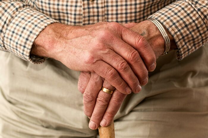 Elderly person's hands resting on a cane, representing patients' regrets shared by hospital workers.
