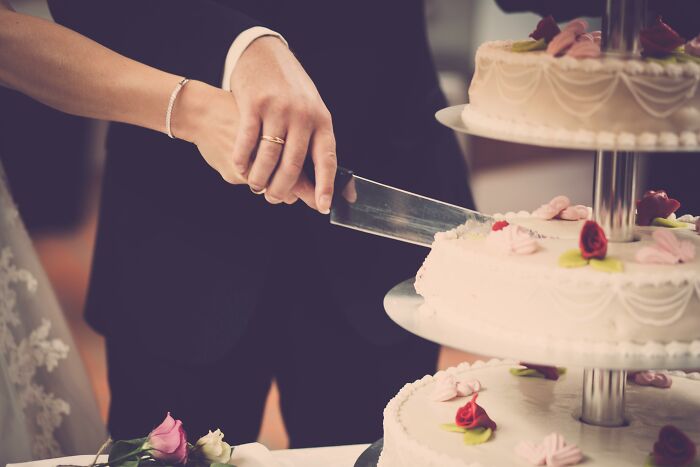 Couple cutting wedding cake with a knife, hands together, symbolizing unity and celebration.