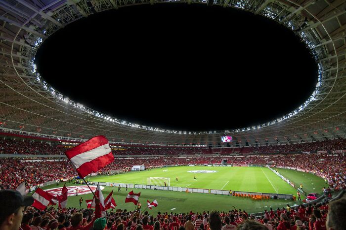 Soccer stadium filled with fans waving red and white flags, showcasing one of the iconic cathedrals of soccer where legends are born.