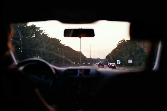 View from inside a car driving on a tree-lined highway at dusk, with misconceptions about traffic in mind.