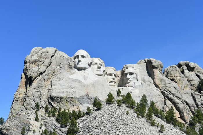Mount Rushmore under clear blue sky, considered overrated by seasoned travelers.