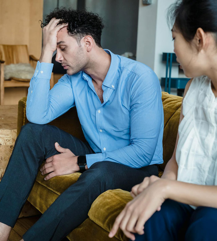 Man in a blue shirt sits with his head in hand, discussing sterilization against partner's wishes. Man in a blue shirt sits with his head in hand, discussing sterilization against partner's wishes.