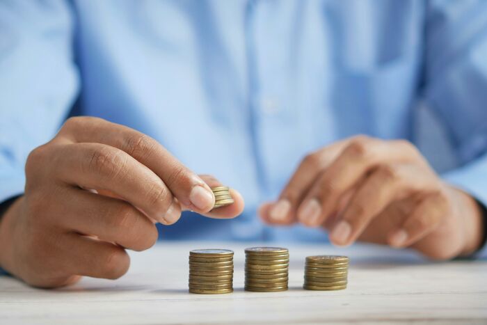 Hands stacking coins on a table, reflecting common financial misconceptions believed to be true.