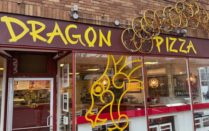 Pizza place exterior with a dragon mural and bicycles above the door. Pizza place exterior with a dragon mural and bicycles above the door.