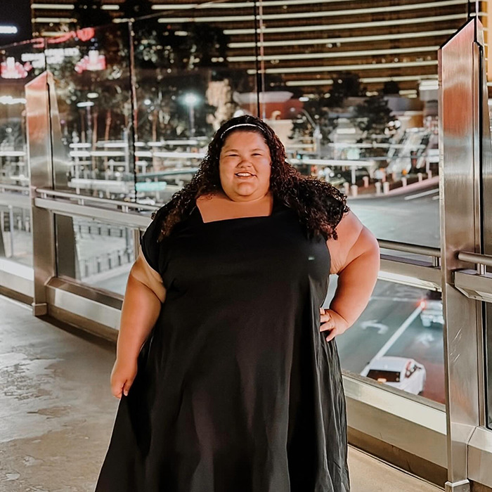 Plus-size woman stands confidently outdoors, addressing flying costs controversy. Plus-size woman stands confidently outdoors, addressing flying costs controversy.