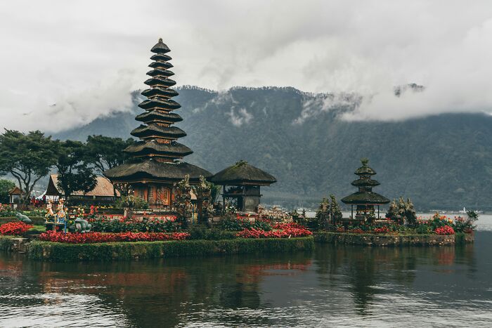 Scenic touristy place with traditional architecture by a lake, surrounded by misty mountains.