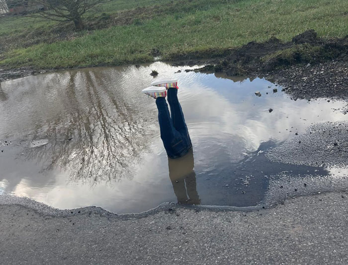 Legs sticking out of a pothole prank, drawing attention to road hazards. Legs sticking out of a pothole prank, drawing attention to road hazards.