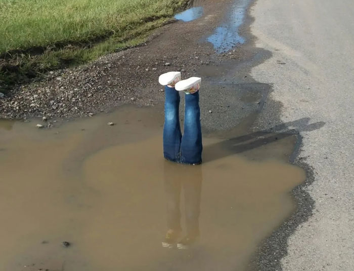 Legs in a pothole prank draws attention, highlighting local road issues. Legs in a pothole prank draws attention, highlighting local road issues.