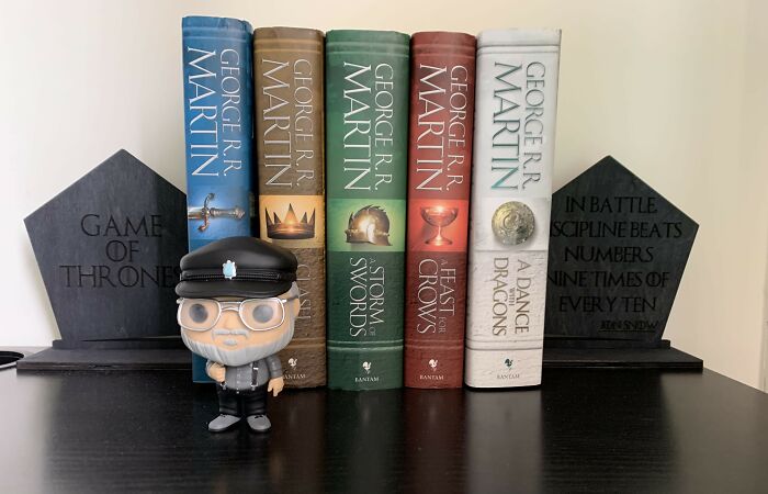Books by George R.R. Martin with a fun figurine, perfect for harmless April Fools' pranks.