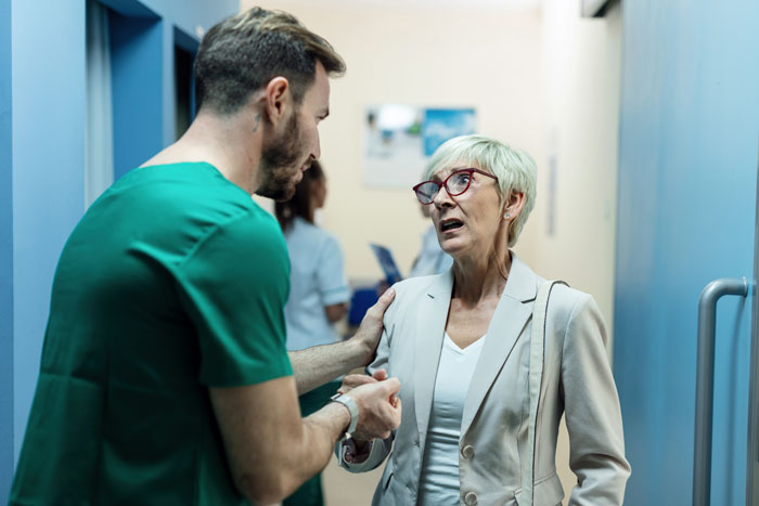 Medical staff talking to a concerned older woman in a hospital corridor. Medical staff talking to a concerned older woman in a hospital corridor.